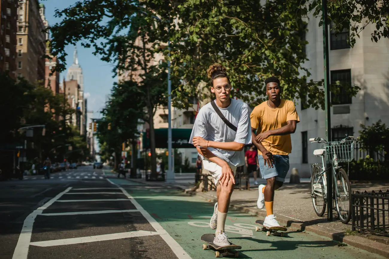 Sporty young diverse men riding skateboards on road on sunny day